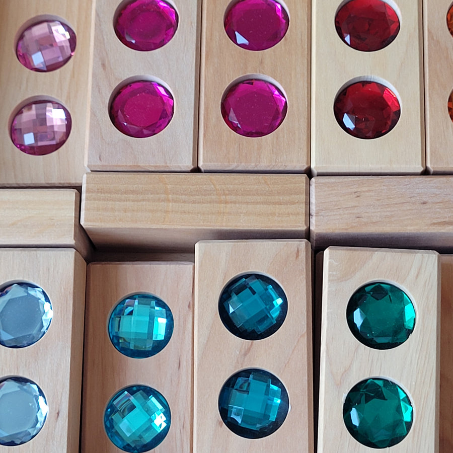 Close-up of Bauspiel Color Track blocks with large faceted gems in pink, teal and blue