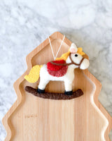 Felt rocking horse ornament, side view, showing the stitched bridle and yellow tail · view 2