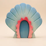 Wooden shell house, a scallop shell standing open with a coral pink doorway at its center · view 1