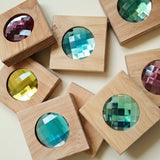All 8 Bauspiel Giant Sparkling Blocks laid out, each square wooden block holding a large faceted gem in pink, blue, green, yellow and teal · view 1