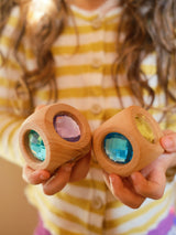 A child holding two Bauspiel Magic Cube Pastel wooden cubes with pastel gems · view 1