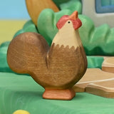 Wooden rooster set among hens and chicks in a farmyard play scene · view 3